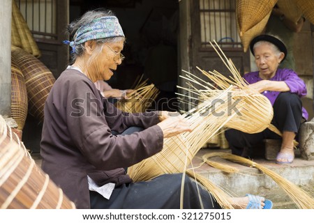 Hung Yen, Vietnam - July 26, 2015: Old women weaves bamboo fish trap at Vietnamese traditional crafts village Thu Sy, Hung Yen province.