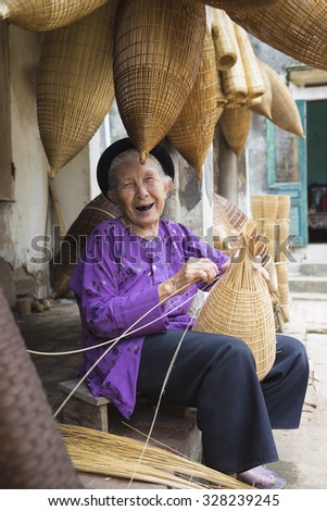 Hung Yen, Vietnam - July 26, 2015: Old woman weaves bamboo fish trap at Vietnamese traditional crafts village Thu Sy, Hung Yen province.