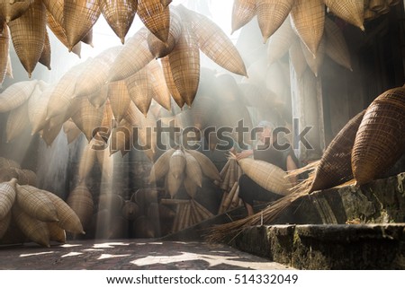 Hung Yen, Vietnam - July 9, 2016: Old house yard with many bamboo fish trap and female craftsman making traditional bamboo fish trap at her old house in Thu Sy trade village
