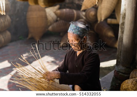 Hung Yen, Vietnam - July 9, 2016: Female craftsman making traditional bamboo fish trap at her old house in Thu Sy trade village