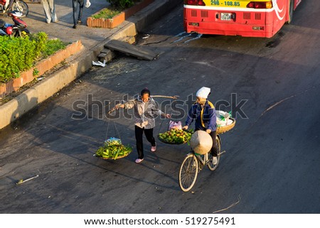 Hanoi, Vietnam - July 23, 2016: Aerial view of Vietnamese woman vendors carrying fruit on Yen Phu street in early morning