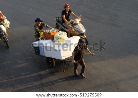 Hanoi, Vietnam - July 23, 2016: Aerial view of Vietnamese women transporting fruit by pull cart on Yen Phu street in early morning