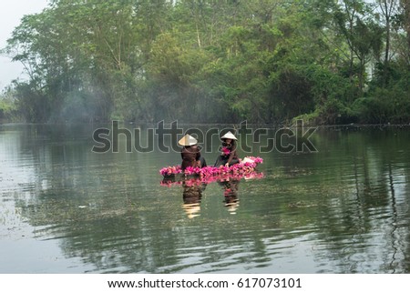 Ninh Binh, Vietnam - Oct 9, 2016: River scene with smoke, a boat carrying girls wearing traditional dress Ao Dai, conical hat, and flower, in Yen stream