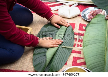Child wear traditional dress Ao Dai learning to make Chung cake by hands closeup, Chung cake is the most important traditional Vietnamese lunar New Year (Tet) food.