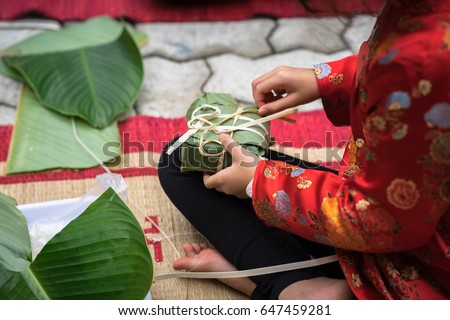 Child wear traditional dress Ao Dai learning to make Chung cake by hands closeup, Chung cake is the most important traditional Vietnamese lunar New Year (Tet) food.