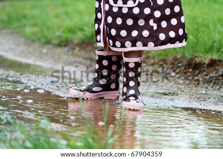 Child's feet playing in a mud puddle. Selective focus on little girl with extreme shallow DOF. Some blur on lower portion.