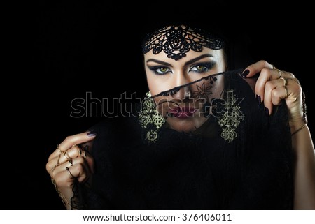 Beautiful caucasian young woman with black veil on face, fency arabian costume