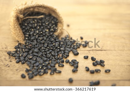 Sack of black beans spill beans all over rustic table