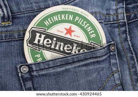 AMELAND, HOLLAND - 2 JUNE, 2016.: Berrmats from Heineken Lager Beer in vintage background , it was first brewed by Gerard Adriaan Heineken in 1873 and blue jeans.