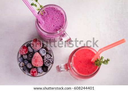 Summer berries smoothie in the jars on white rustic background. View from above, top studio shot