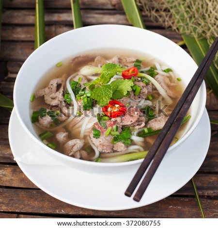 Traditional Vietnamese beef soup pho on a wooden background