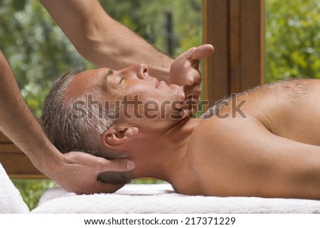 Side profile of a mature man receiving a massage from a massage therapist