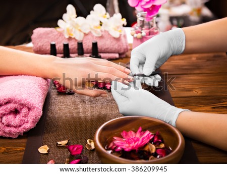 Closeup finger nail care by manicure specialist in beauty salon.