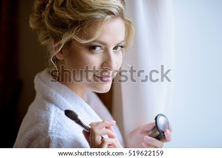 Wedding makeup artist making a make up. Beautiful sexy model girl indoors. Beauty woman with curly hair. Female portrait of bride. Bridal morning of a cute lady. Close-up hands near face