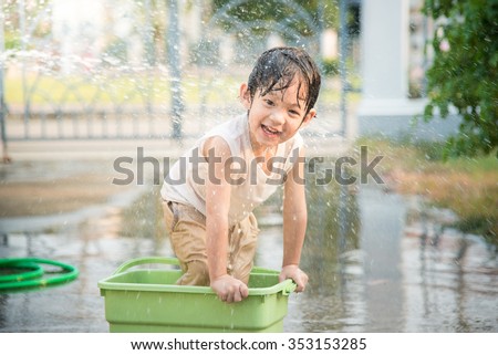 Cute asian boy has fun playing in water from a hose