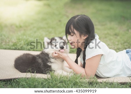 Beautiful asian girl playing with siberian husky puppy in the park,vintage filter