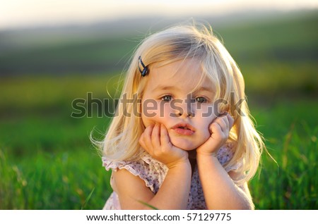 Beautiful blonde girl outside in a field with sunlight on her hair. - stock photo