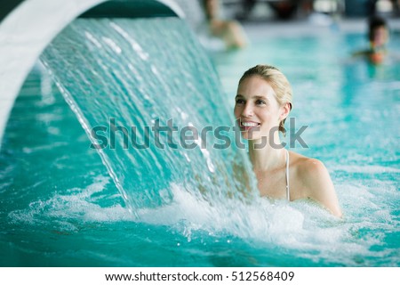 Woman enjoying hydrotherapy and water stream in spa pool