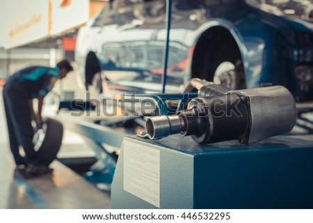 Serviceman checking suspension in a car at garage , process in vintage style