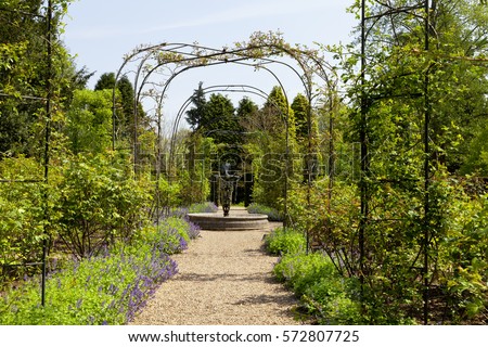 english spring flower garden with a gravel path under an archway leading to a water fountain - Flower Garden Path english spring flower garden with a gravel path under an archway leading to a water fountain - Flower Garden Path