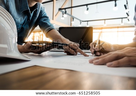 Two Architects engineer discussing data working and tablet, laptop with blueprint - Closeup on hands and project print.
