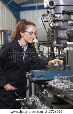 Female Apprentice Engineer Working On Drill In Factory