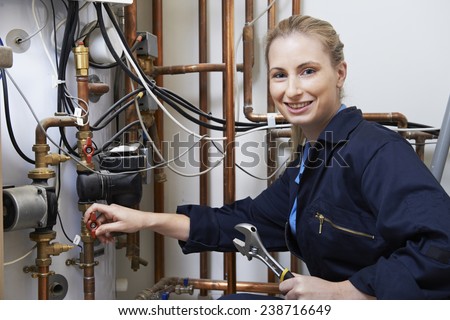 Female Plumber Working On Central Heating Boiler