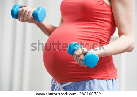 Close Up Of Pregnant Woman Exercising With Weights