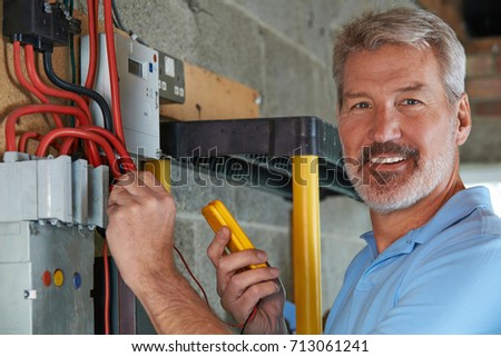 Portrait Of Electrician Standing Next To Fuseboard