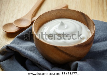 Yogurt in wooden bowl on wooden background with blue cotton and wooden spoon. plain yoghurt. yogurt. yoghurt.