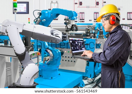 Engineer using laptop computer for maintenance automatic robotic hand machine tool at the factory