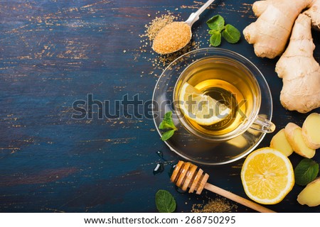 Cup of Ginger tea with lemon and honey on dark blue background, top view