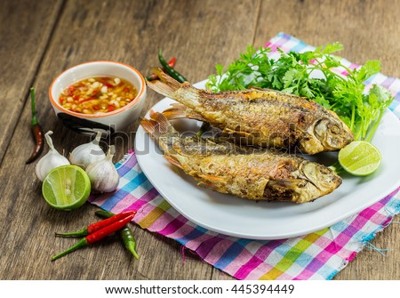 Fried fish on plate with chili sauce and vegetables