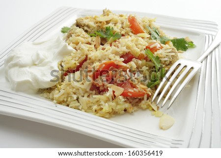 Homemade chicken biriyani, garnished with coriander leaves and toasted almond flakes, and served with a dollop of yoghurt. - stock photo
