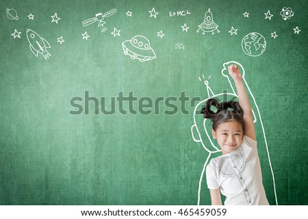 Happy little asian girl kid in astronaut suit doodle drawing+ universe space out of earth planet on school green class chalkboard chalk board background Creative innovation educational conceptual idea