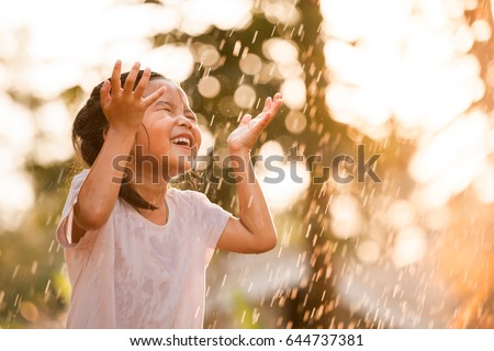 Happy asian little girl having fun to play with the rain in vintage color tone