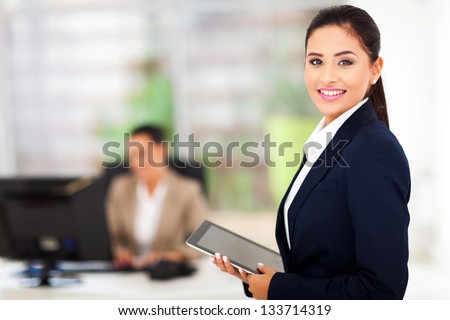 beautiful modern businesswoman holding tablet computer with colleague on background
