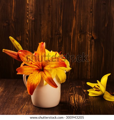 Bunch of orange and yellow lilly flowers on vintage wooden dark table. Space for text. Greeting card. Selective focus. Square image