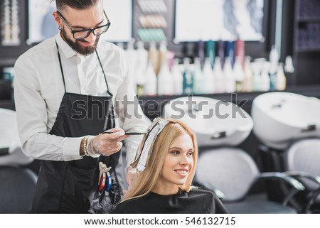 Smiling stylist is dying long hair
