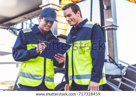 Outgoing man noting document near happy comrade