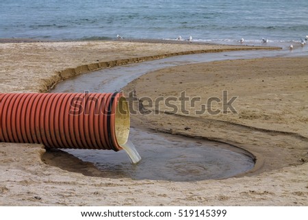 environmental pollution on the beach. Waste pipe or drainage polluting environment. Birds drink waste water