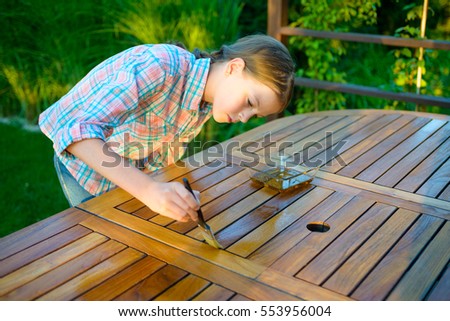 young pretty girl holding a brush applying varnish paint on a wooden garden table - Garden Furniture Varnish young pretty girl holding a brush applying varnish paint on a wooden garden table - Garden Furniture Varnish