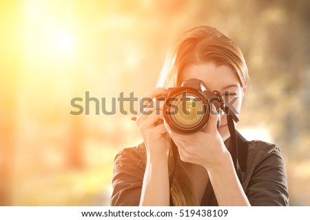 Portrait of a photographer covering her face with the camera.