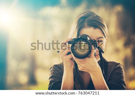 Portrait of a photographer covering her face with the camera.
