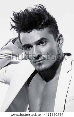 Beautiful athletic bodybuilder male model posing in studio. Expression on camera. Brutal man in leather suit.