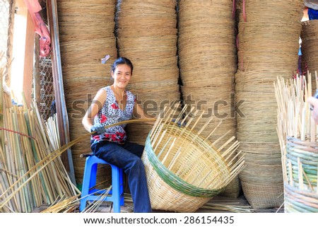 Vinh Long city, Vietnam - 06 May 02, 2015: Unknown, An Asian woman weaving handicraft basket from bamboo. The fruit trader on floating market in the Mekong Delta will need the baskets like these
