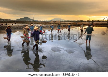 Ninh Thuan Province, Vietnam - February 28, 2016 :the women are working on salt field at dawn. Salt field Hon Khoi in Nha Trang, Viet Nam. Workers transporting salt from the fields Hon Khoi, Viet Nam.