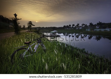 Flamingo Dai Lai, Vinh Phuc province, Vietnam - October 11, 2016 : bike beside the lake in the sunset, warm sunset view and beautiful clouds reflected in water at Flamingo Dai Lai resort