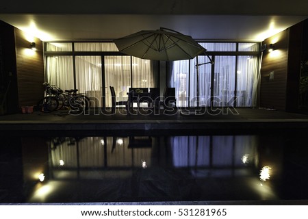 Flamingo Dai Lai, Vinh Phuc province, Vietnam - October 12, 2016 : the living room of a villa overlooking the beautiful pool in night with the reflection of water at Flamingo Dai Lai resort