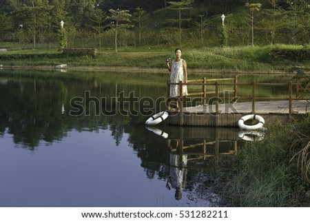Flamingo Dai Lai, Vinh Phuc province, Vietnam - October 13, 2016 :woman standing on the dock watching the beautiful landscape of the autumn to take pictures, at Flamingo resort Dai Lai, Vietnam